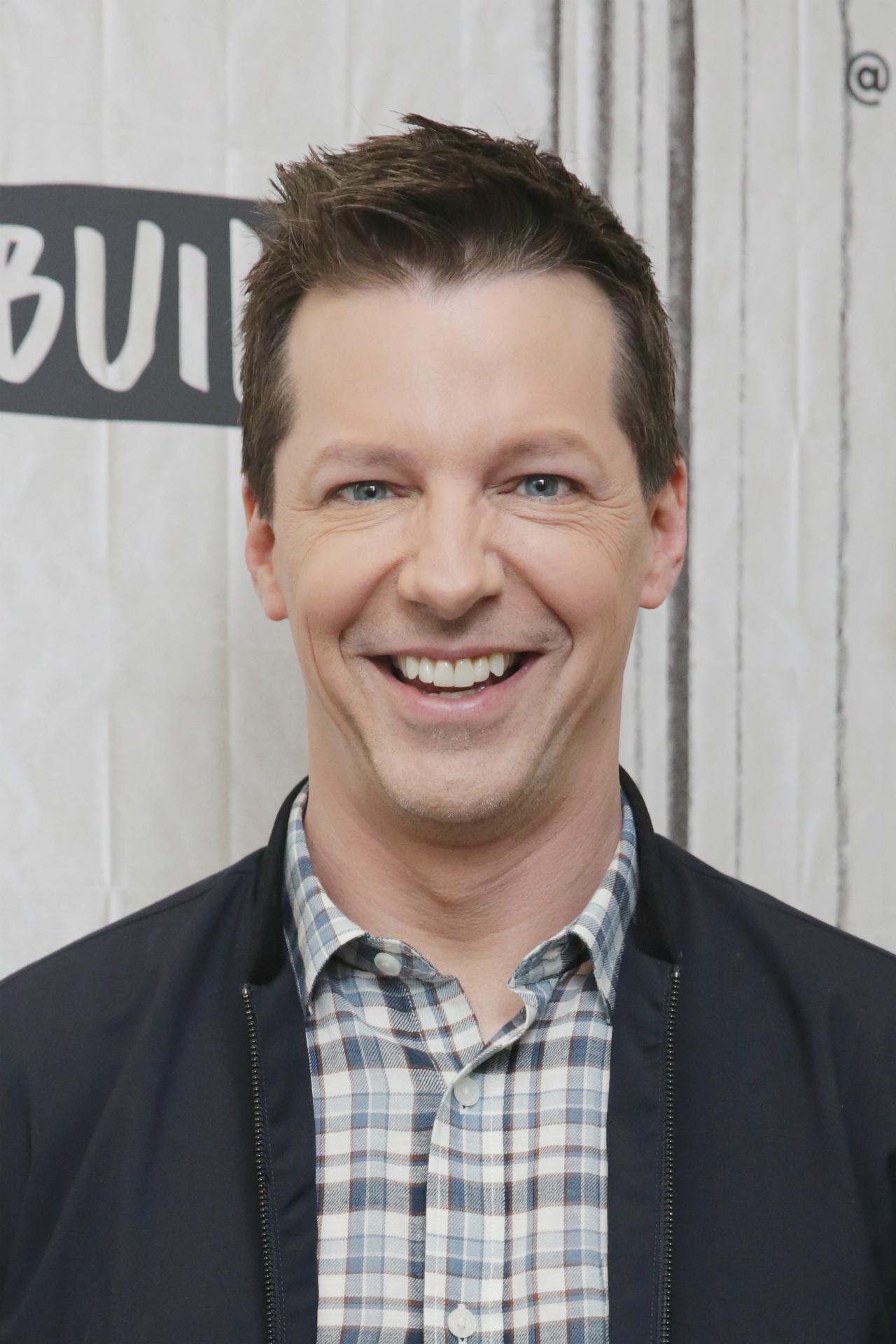 Sean Hayes wears a blue plaid shirt and a blue zip jacket.