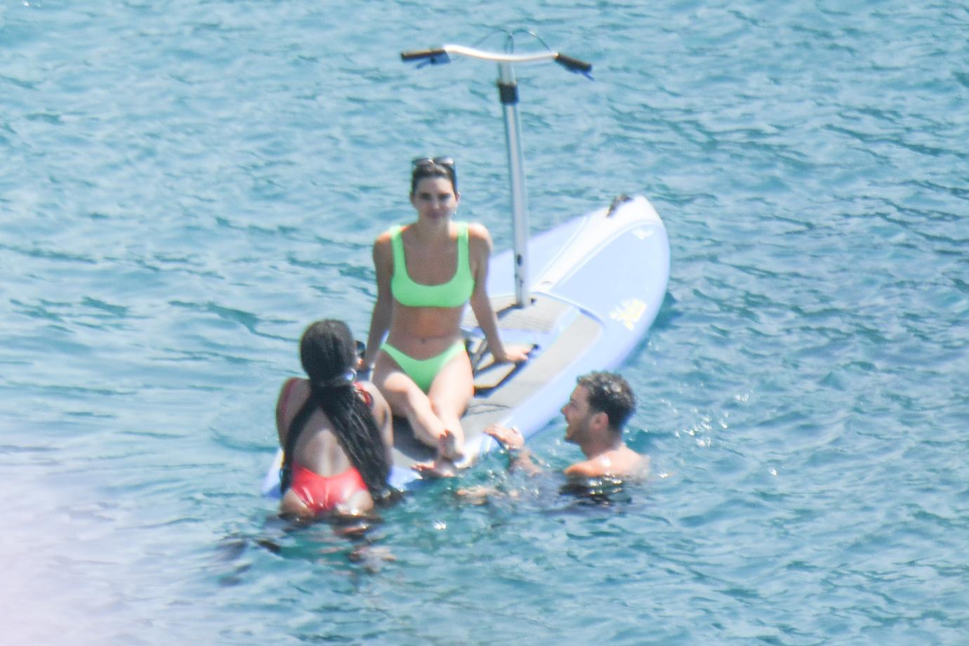 Kendall Jenner wears a neon-green bikini while having fun with friends paddle boarding in Mykonos.