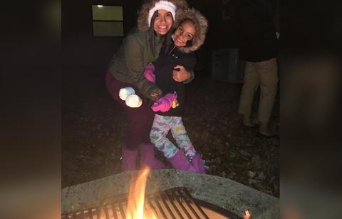 Briana Dejesus holds her kid near a bon fire.