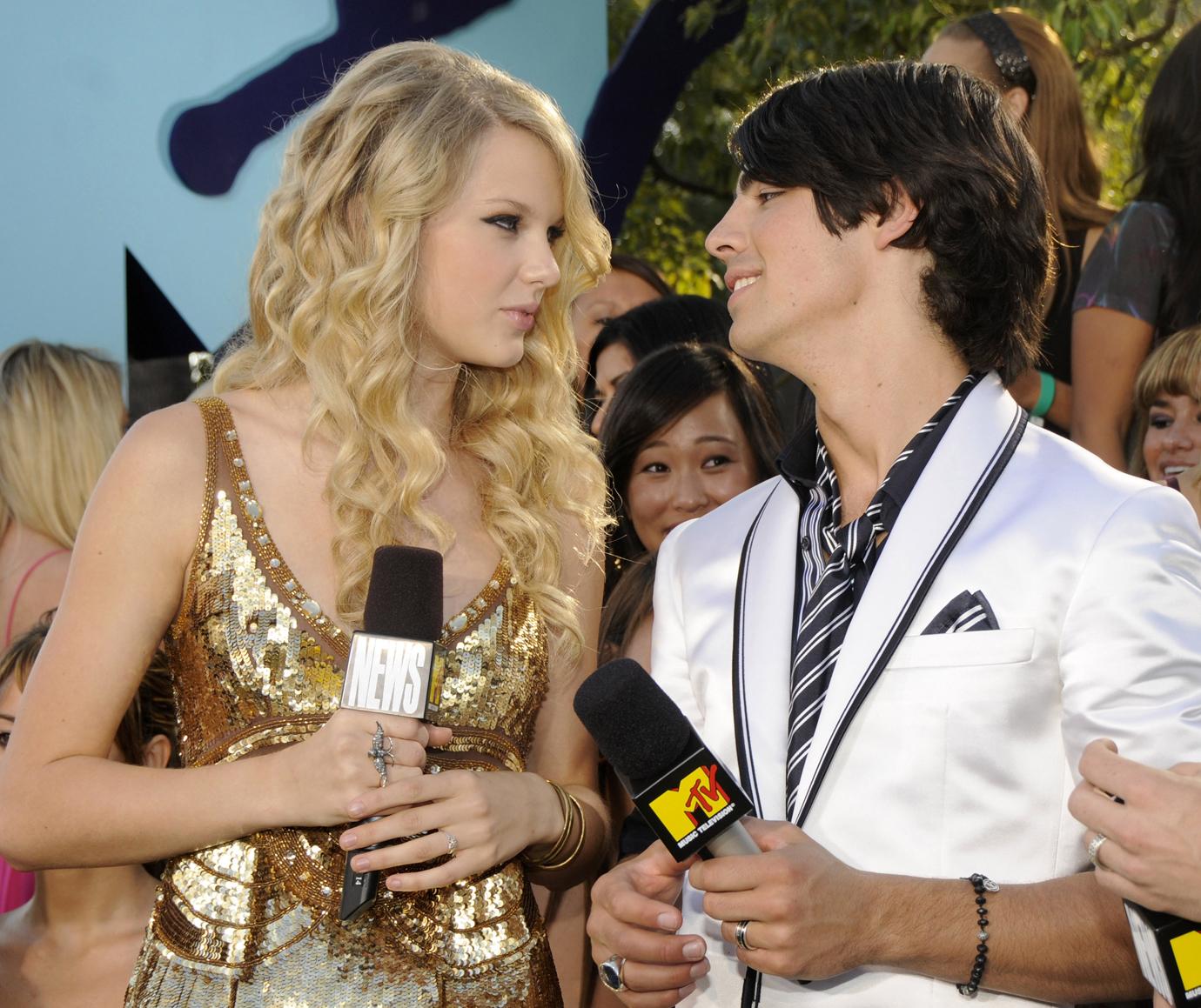 Taylor Swift In Gold Sequin Dress Looking Serious At Joe Jonas in White Suit