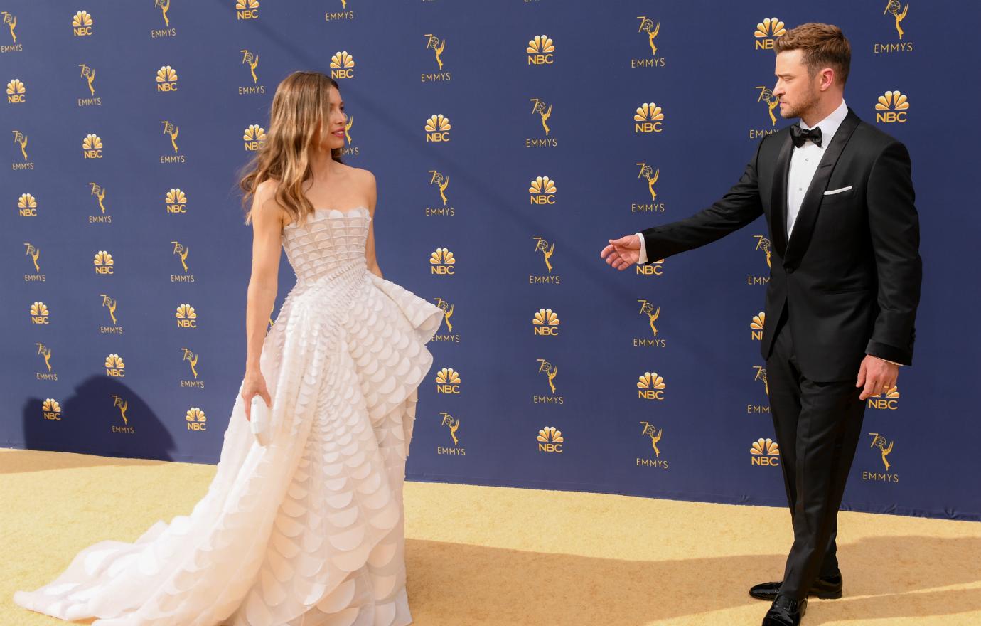 Jessica Biel, in a white, lacy dress with big train, stands on the red carpet next to Justin Timberlake who wears a black tux and white shirt.