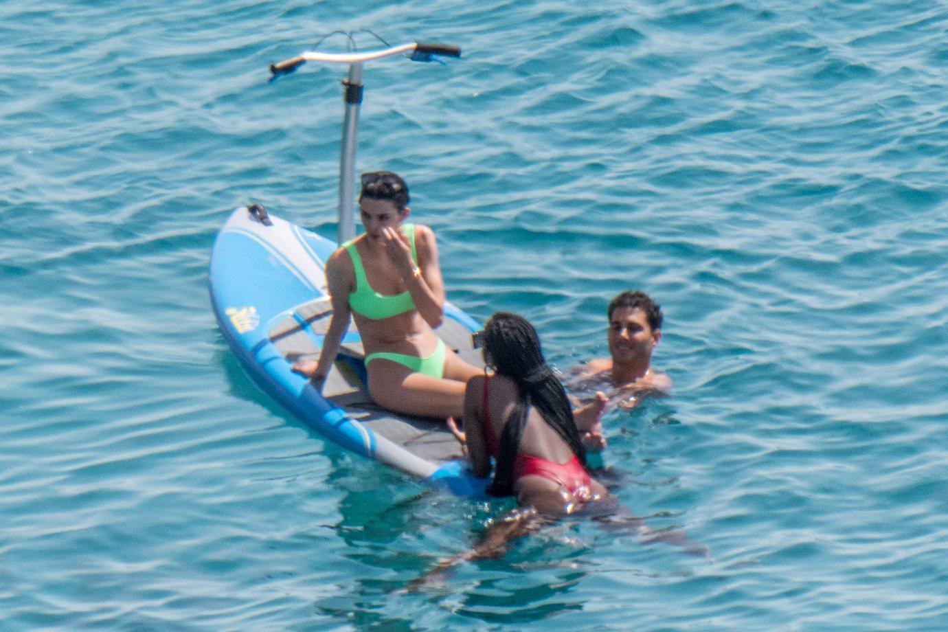 Kendall Jenner wears a neon-green bikini while having fun with friends paddle boarding in Mykonos.