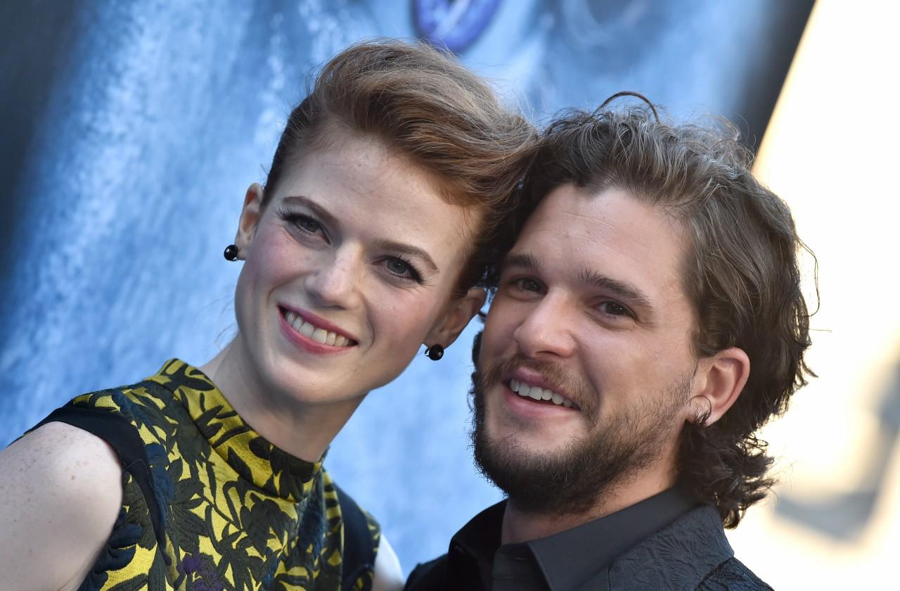 Rose Leslie in black and yellow smiles with Kit Harrington, wearing black