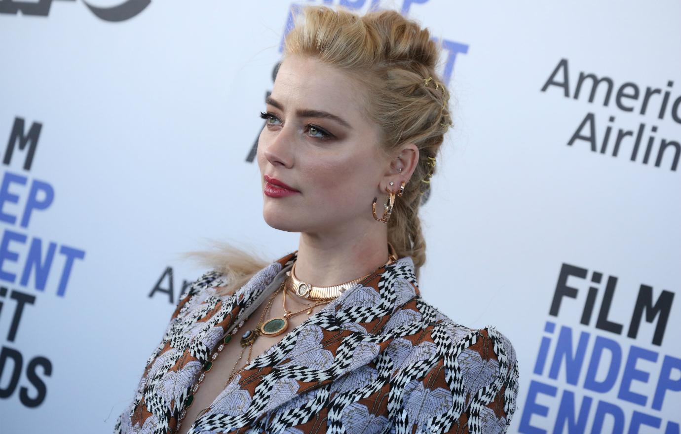 Amber Heard wore a patterned blazer with shoulder pads, accessorized with a gold, neck-hugging necklace.