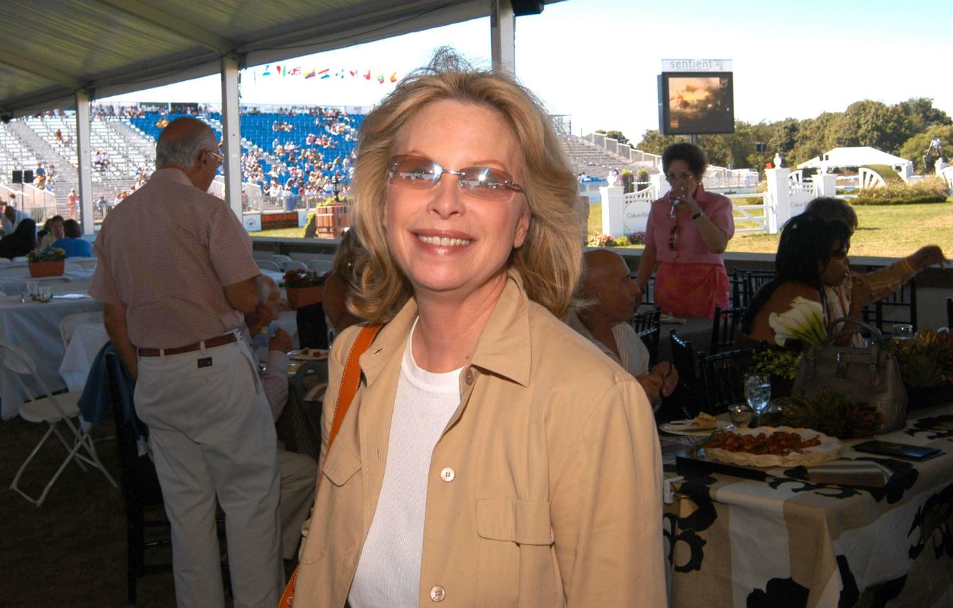 Ronni Chasen wears a white top and brown jacket and sunglasses.