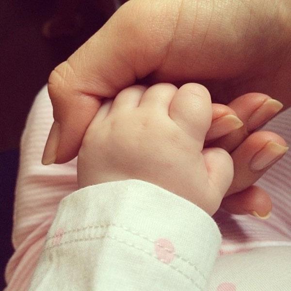 Hilaria Baldwin holding the little hand of she and Alec Baldwin