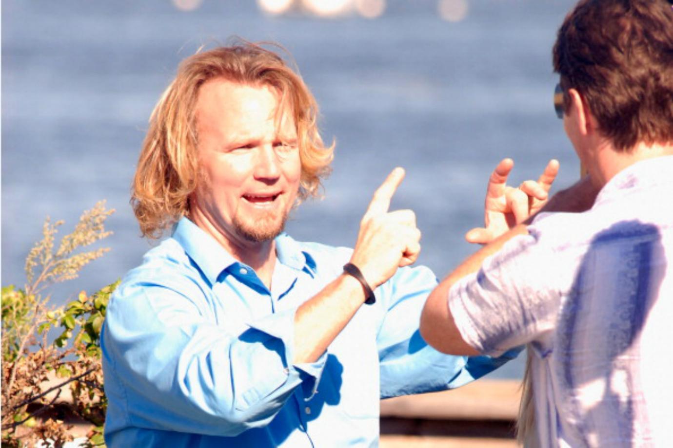 Kody Brown gestures with his hands while speaking to a man.