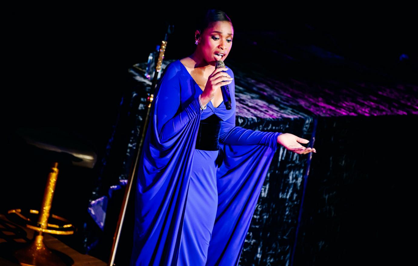 Jennifer Hudson, wearing a power blue gown, sings on stage into a mic.