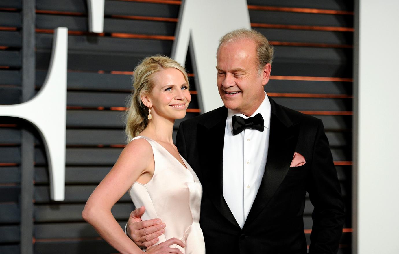 Kelsey Grammer, in a black tux and white shirt, has his arm around Katye Walsh who wears a peach-colored dress on the red carpet.