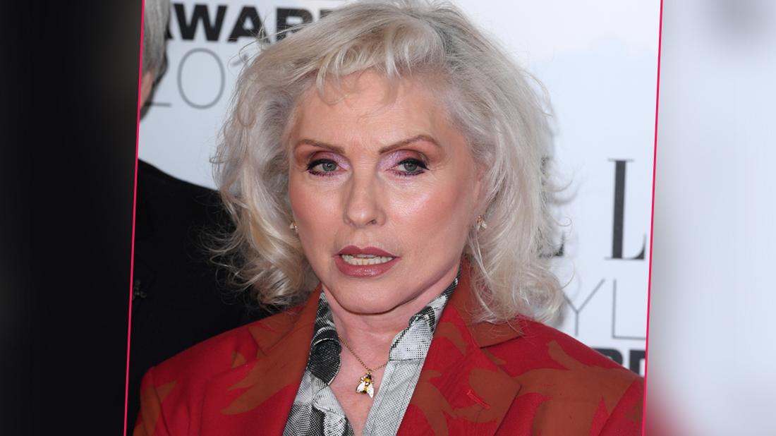 Debbie Harry wearing a red jacket and t shirt with a pattern.