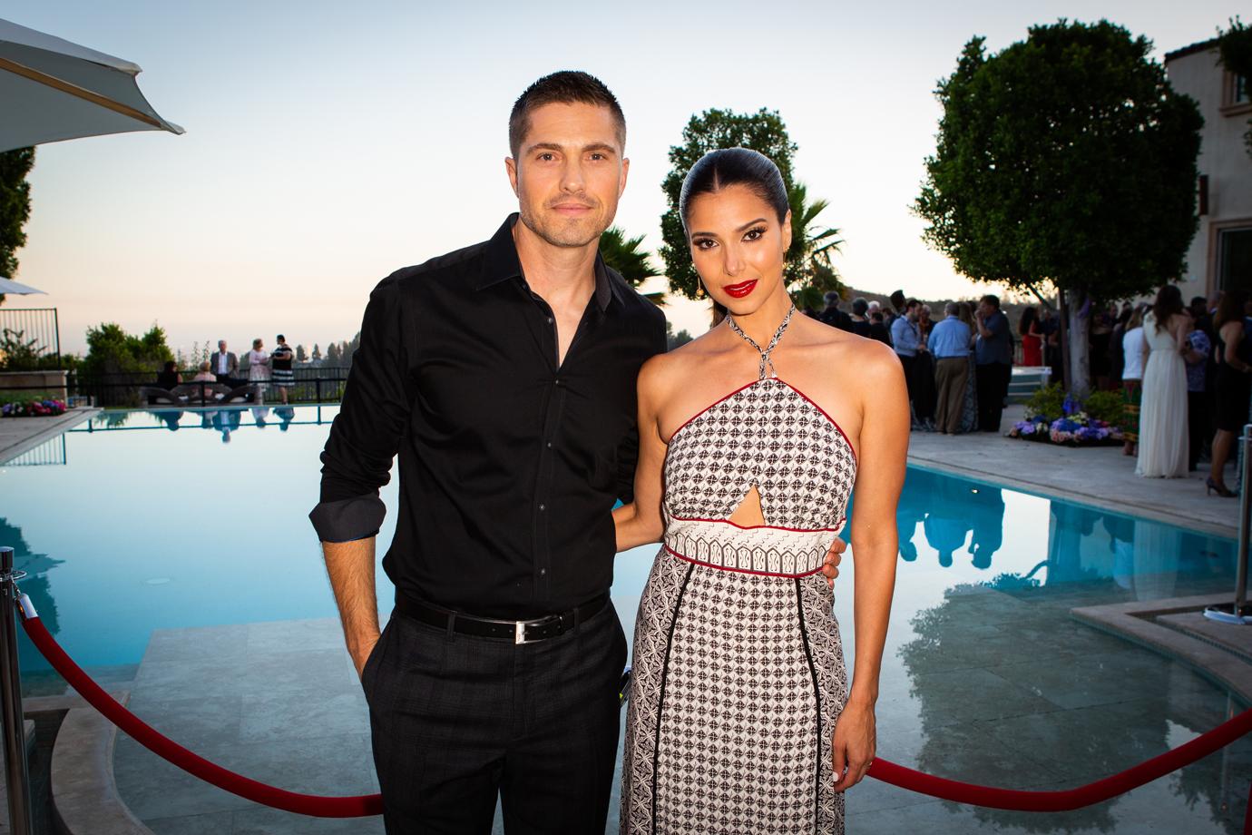 Eric Winter and Roselyn Sánchez Smiling In Front of Pool at Outdoor Party