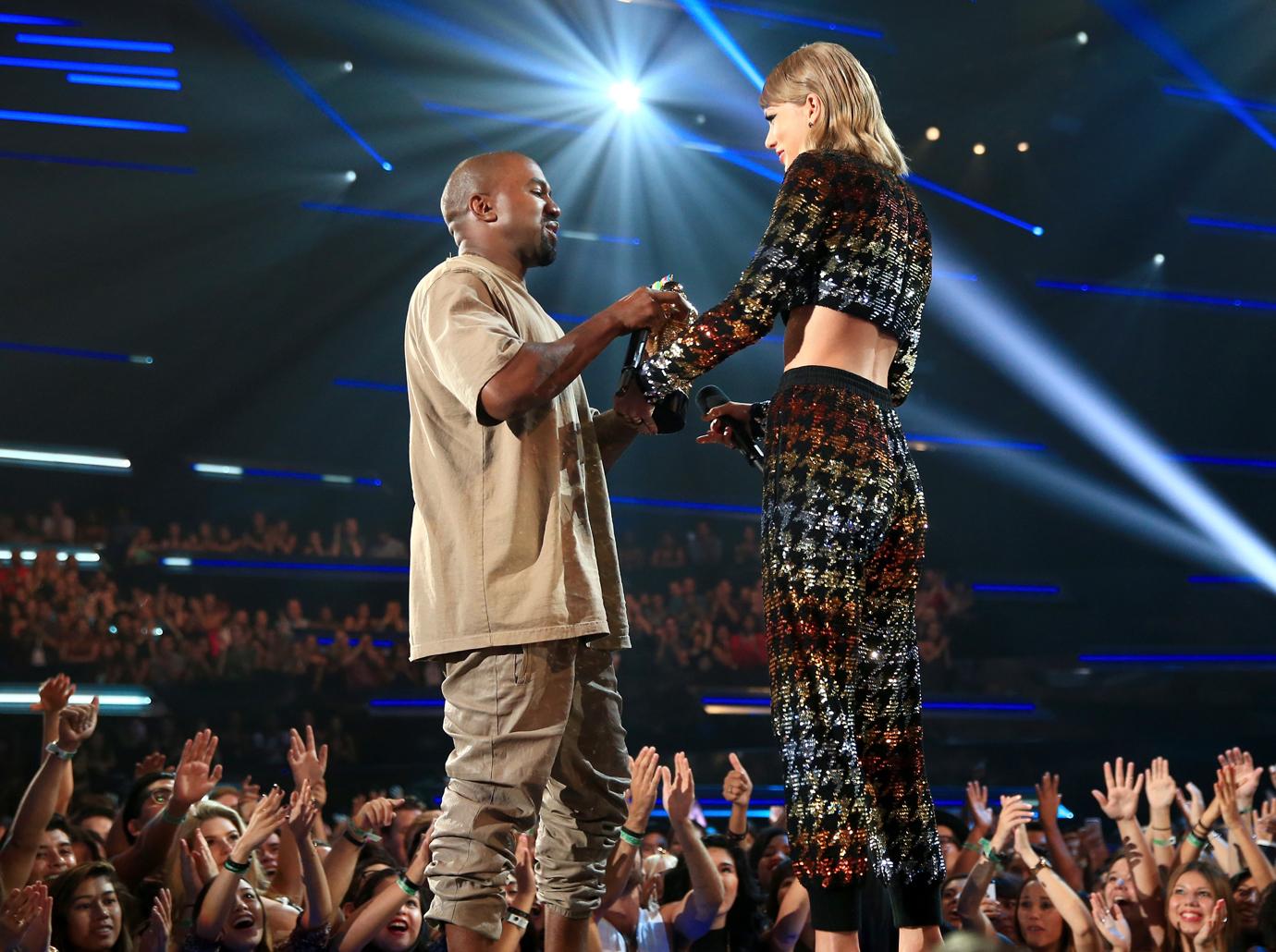 Kanye West In All Beige Attire Handing Award to Taylor Swift On Stage Wearing a Sparkly Outfit