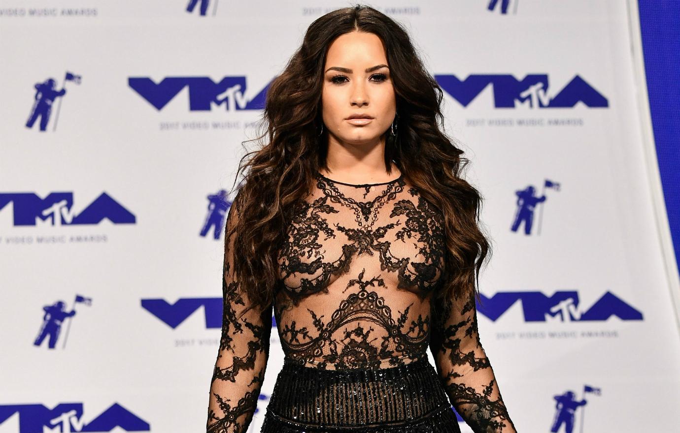 Demi Lovato dazzled in a lacy, see-through blouse with matching black pants.