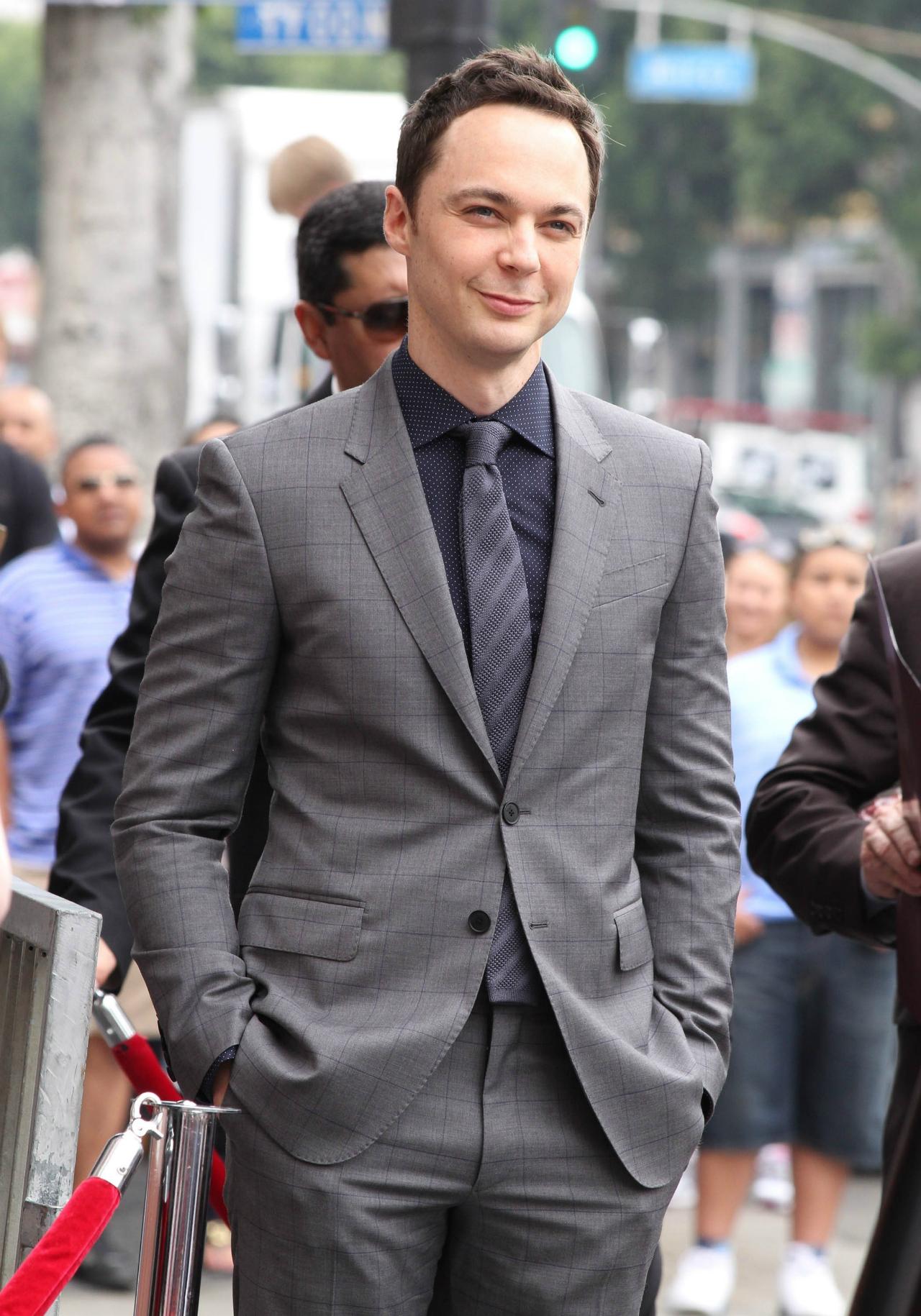 Jim Parsons wears a gray suit with blue plaid, a blue polka dot shirt, and a blue gray tie.