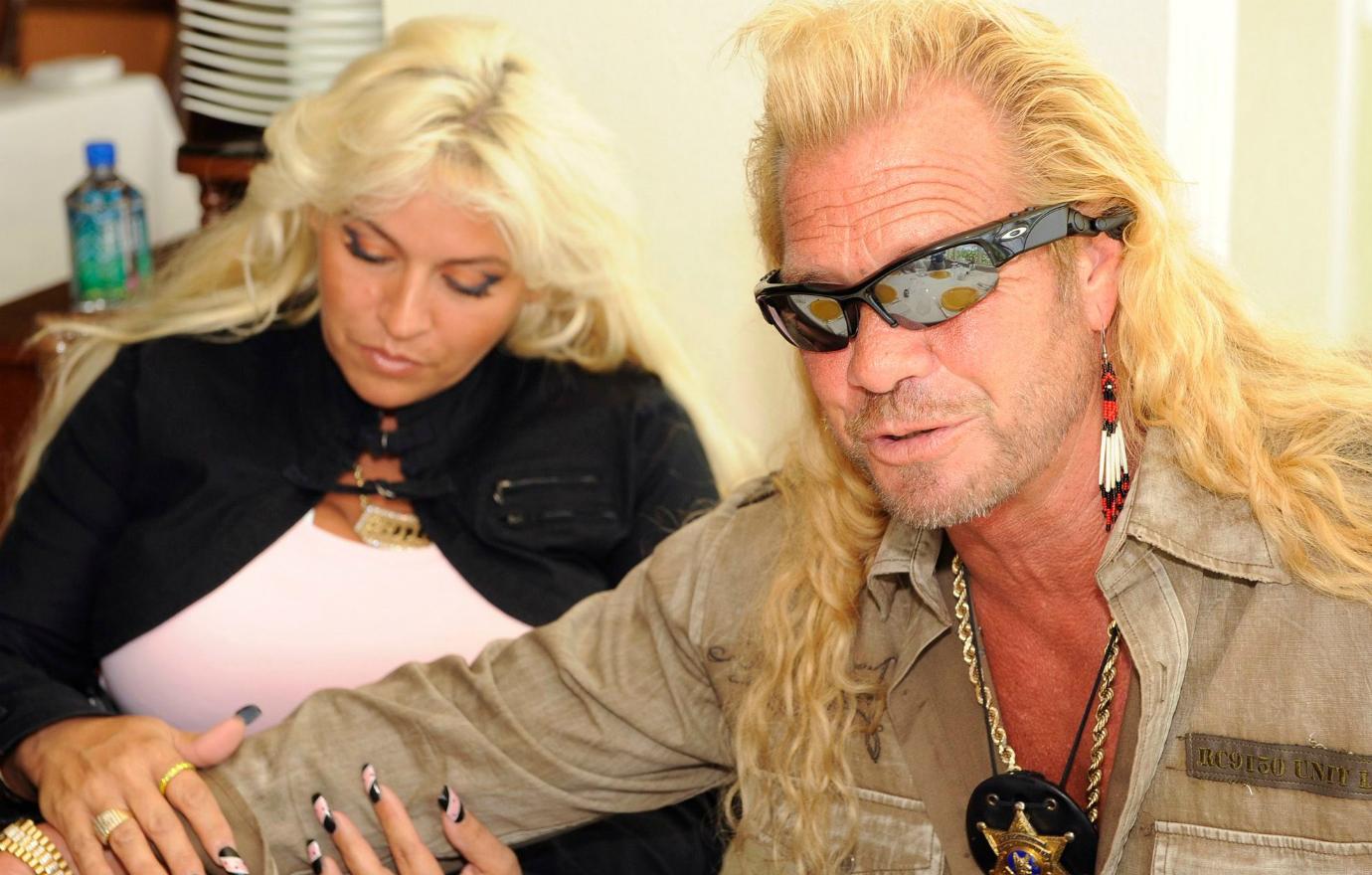 Dog the Bounty Hunter wore dark shades with a tan buttoned shirt that was not buttoned as his wife, Beth Chapman, wore a pink top with a black jacket.