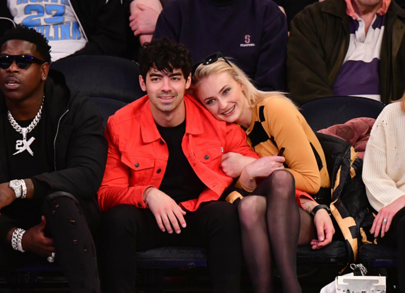 Joe Jonas and Sophie Turner sit next to each other.