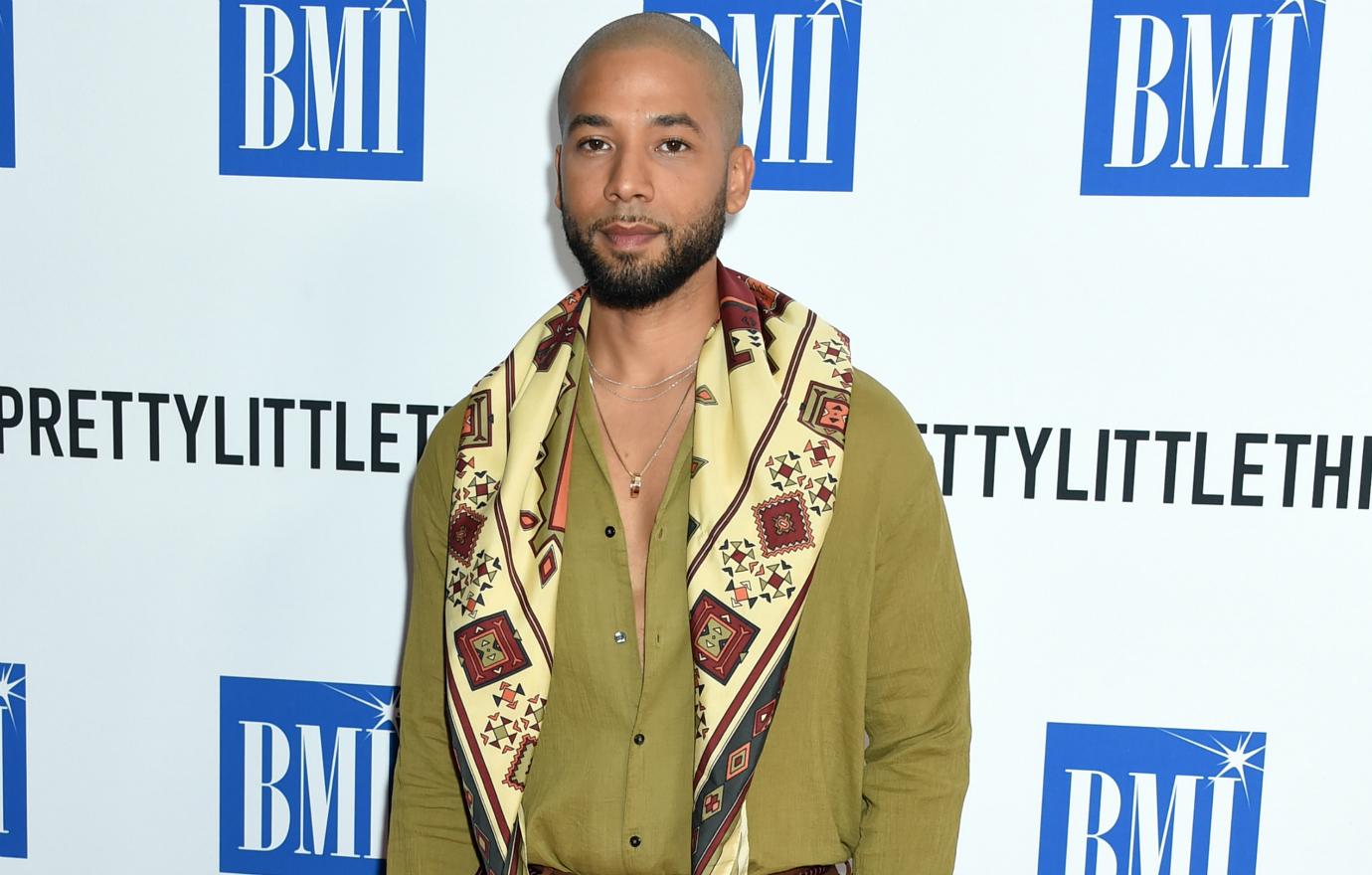 Jussie Smollett wore a brown oxford shirt tucked into a deeper shade of brown slacks — accessorized with a matching scarf.