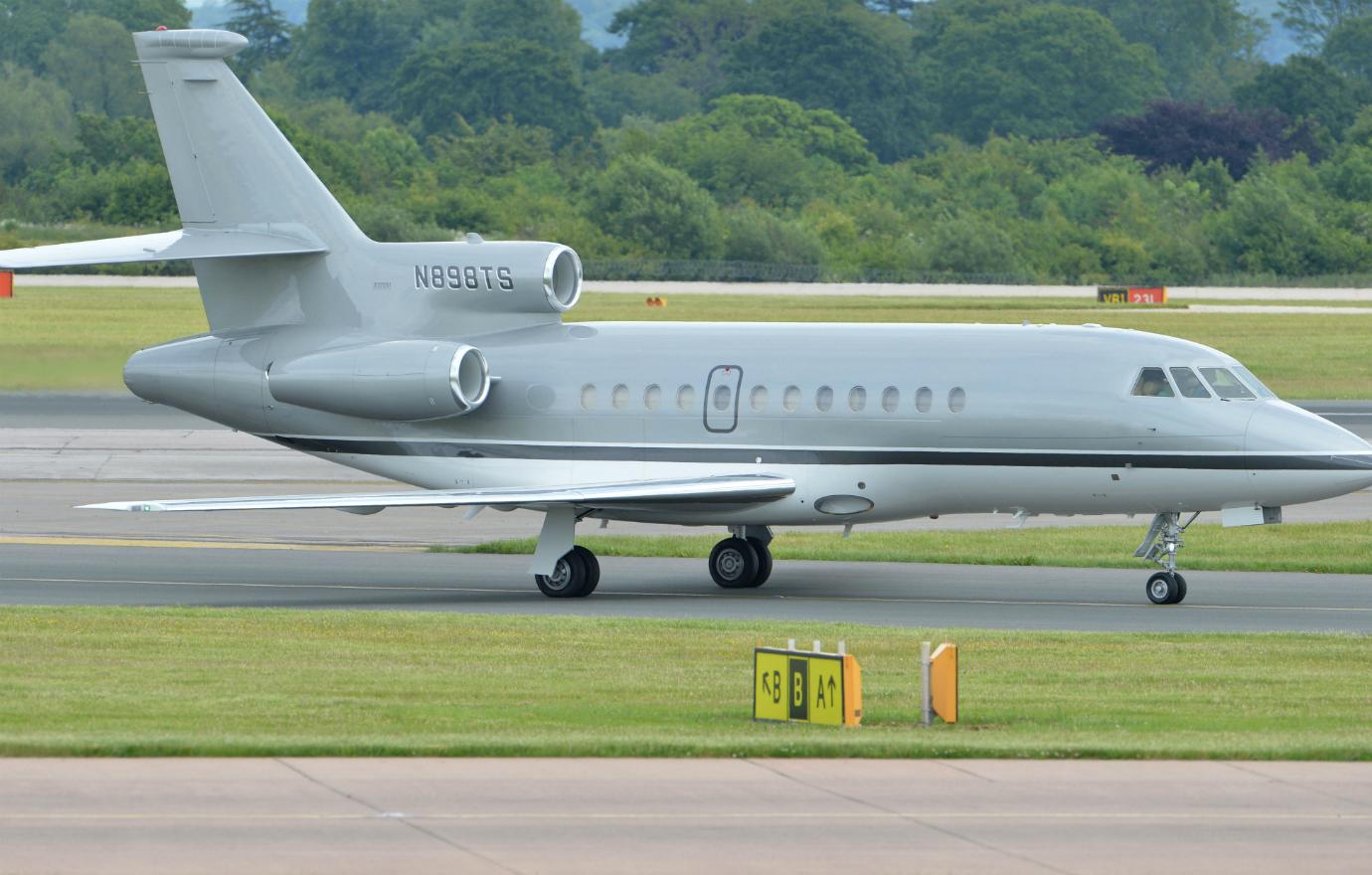 A private jet sits on the runway, its windows blacked out.