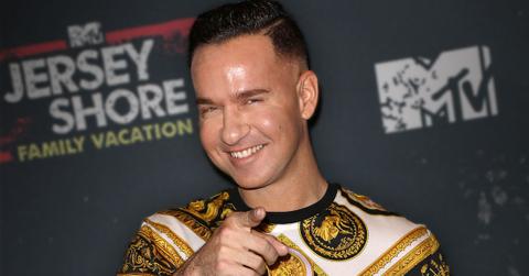 Smiling Mike Sorrentino Pointing At Camera Wearing A Black Gold And White Top