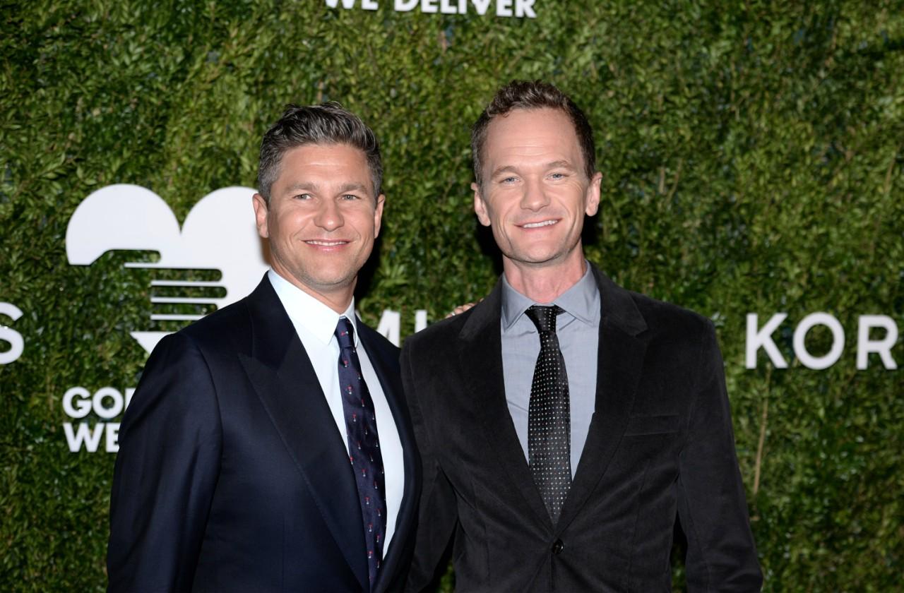 David Burtka and Neil Patrick Harris, both in black suits, smile on the red carpet