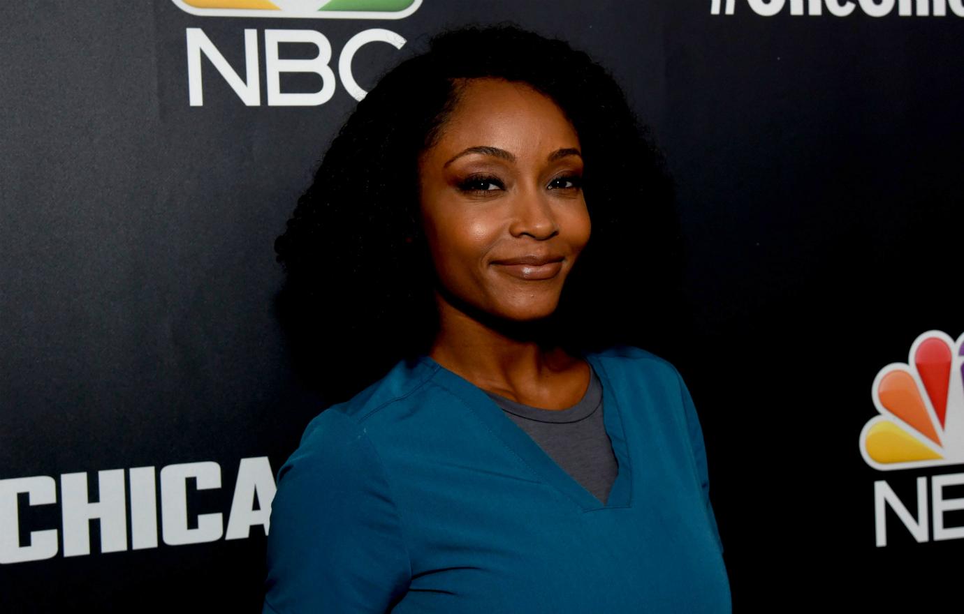 Yaya DeCosta in a a blue top, smiles from the NBC red carpet.