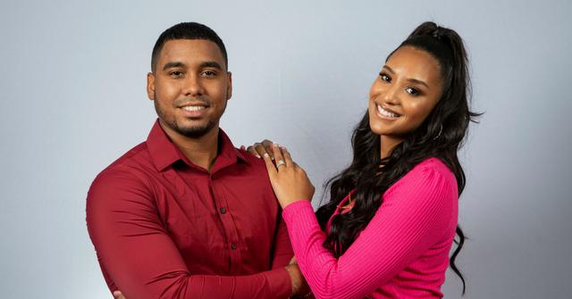 Pedro Jimeno wears a red shirt and poses with wife Chantel Everett who wears a red dress.