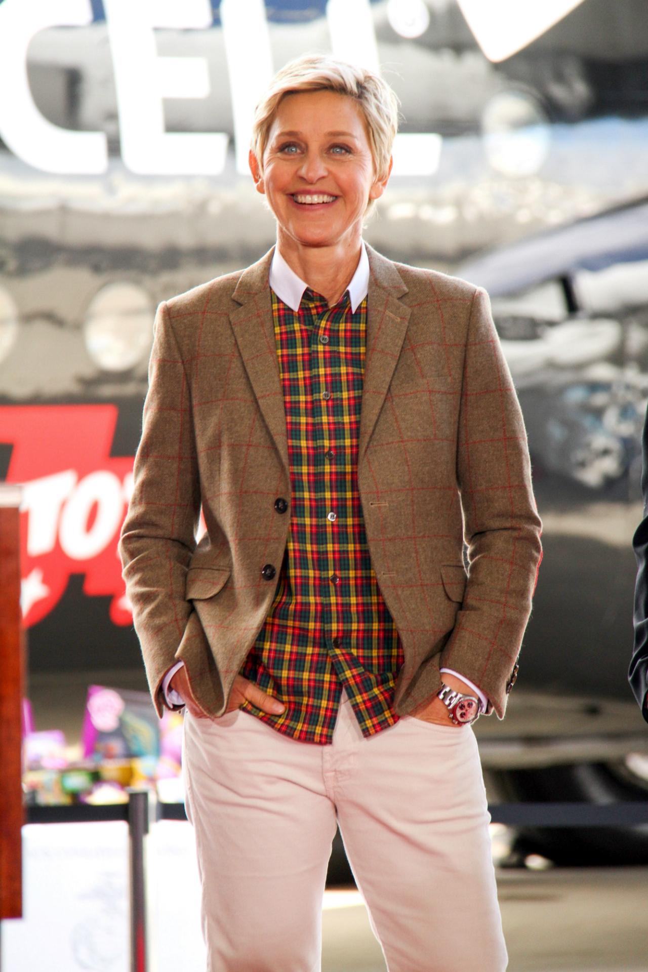 Ellen DeGeneres wears white pants, paired with a brightly colored plaid shirt and brown plaid jacket.