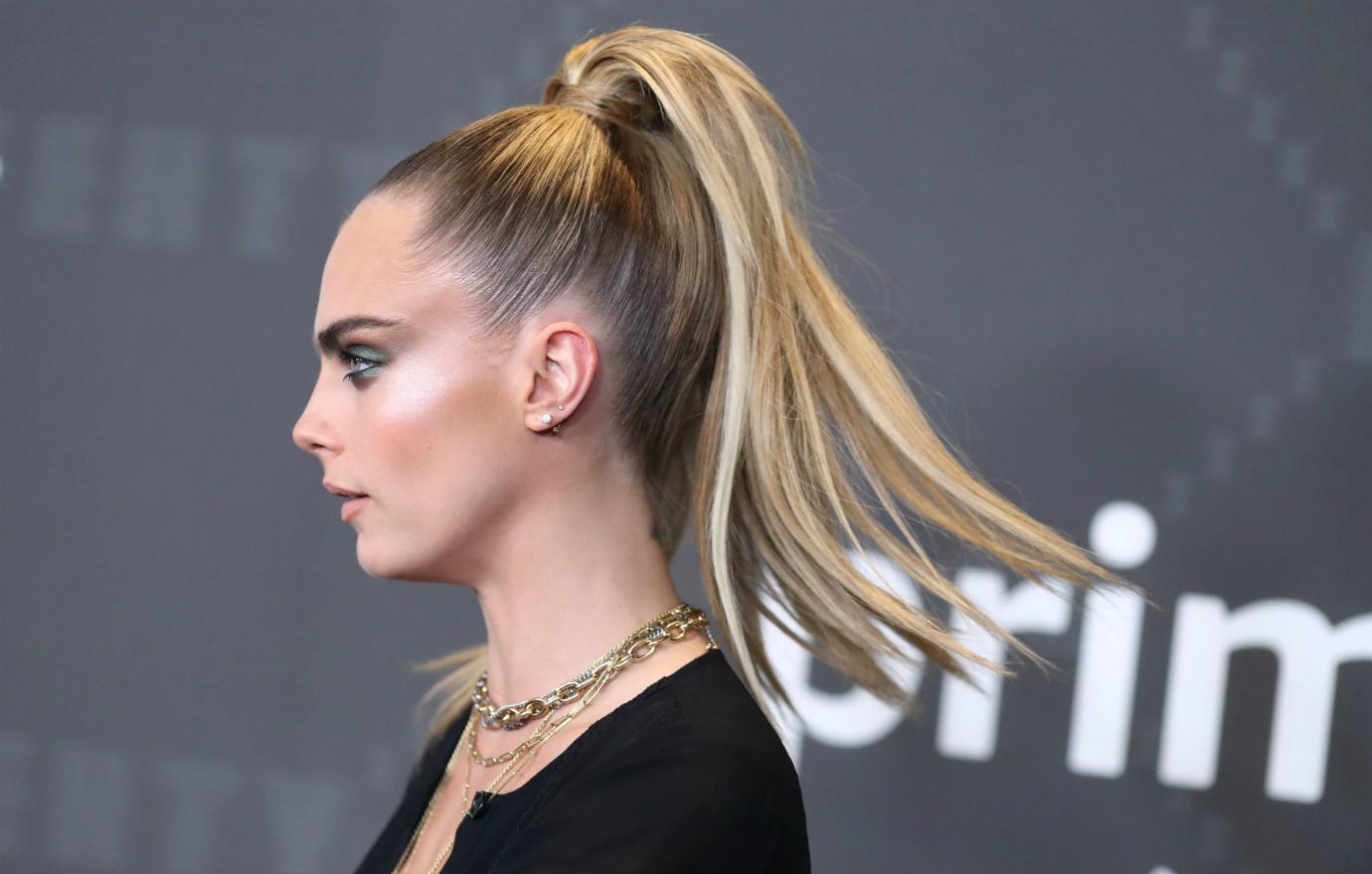 Profile shot of Cara Delevinge who wears a black top and has her hair in a ponytail.