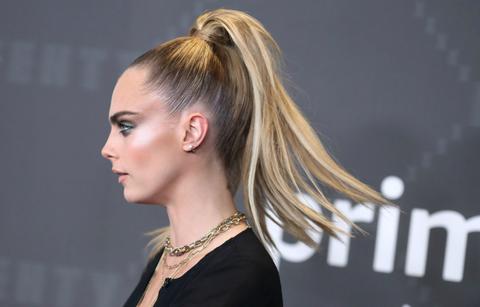 Profile shot of Cara Delevinge who wears a black top and has her hair in a ponytail.