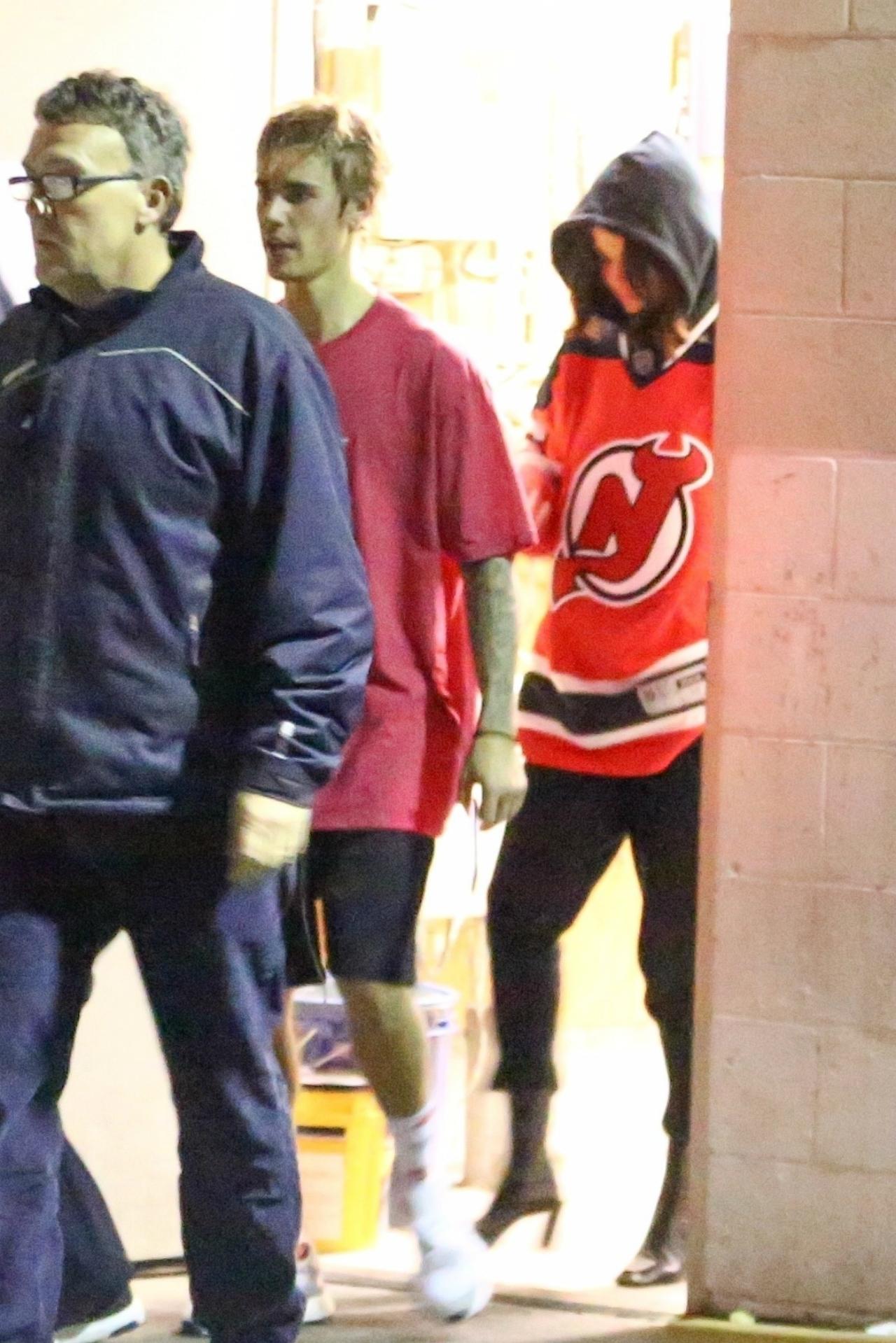 Selena Gomez wears Justin Bieber's red hockey jersey, Justin Bieber wears a red t-shirt and black shorts.