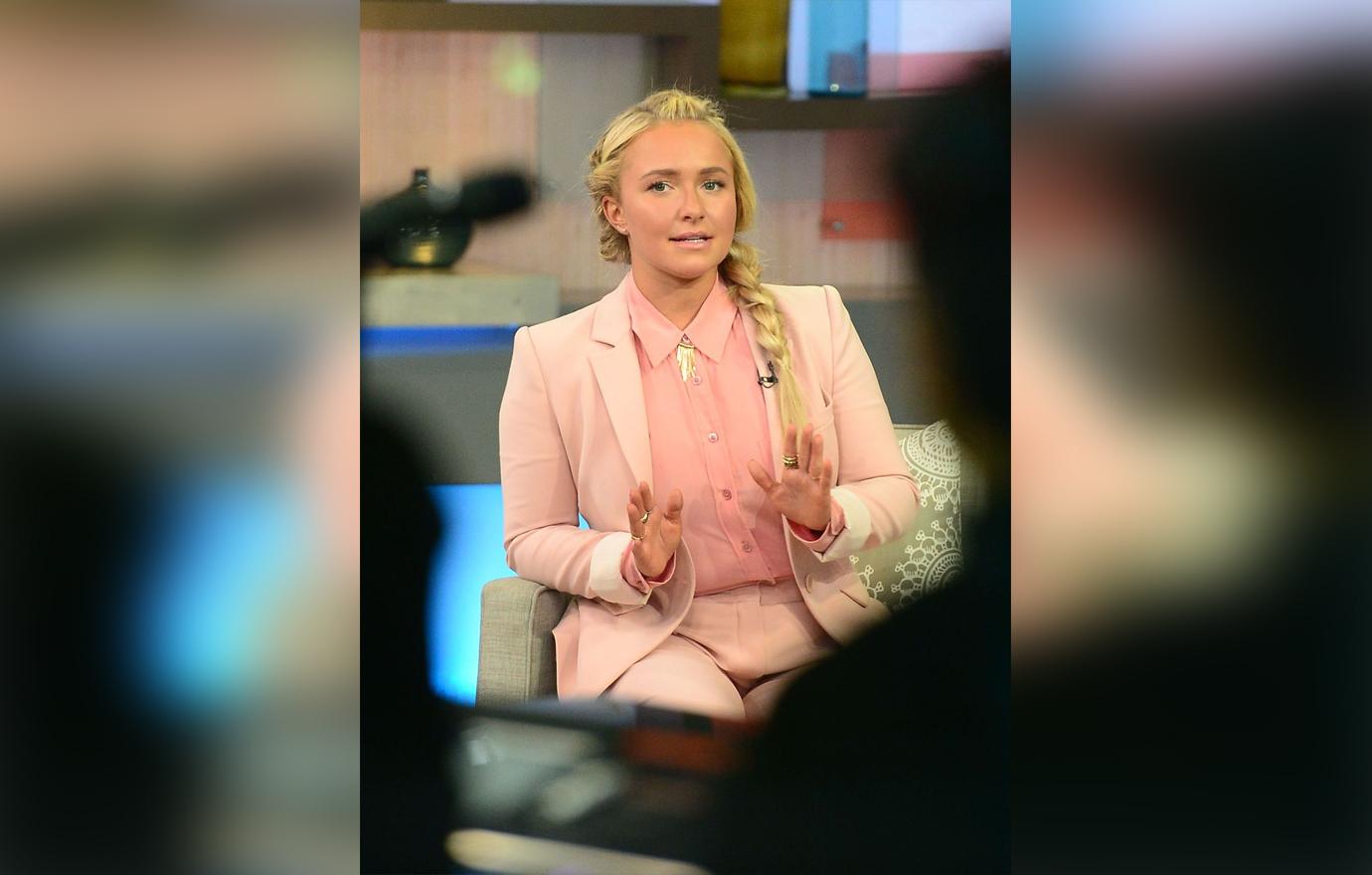 Hayden Panettiere Sits Inside a Television Studio Looking Serious Wearing Full Pink Suit and Blouse Ensemble