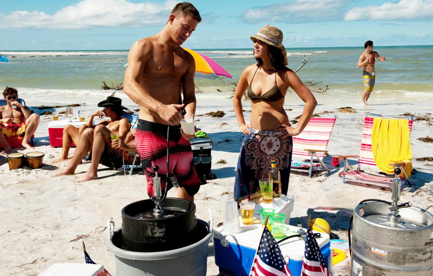 Channing Tatum stood shirtless in a pair of red shorts alongside Olivia Munn who wore a green bikini top and colorful sarong.