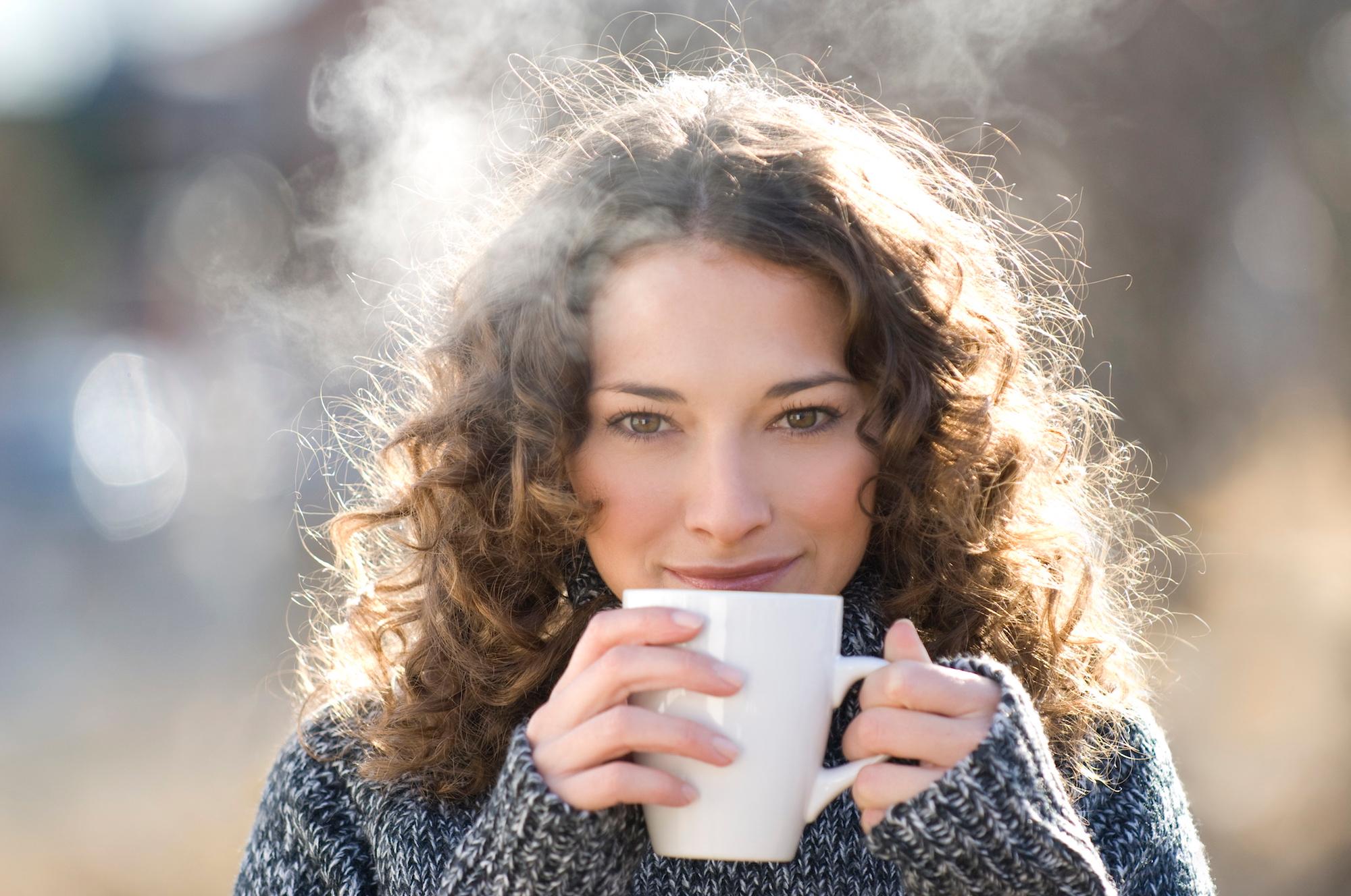 Brunette woman in pullover drinking hot tea