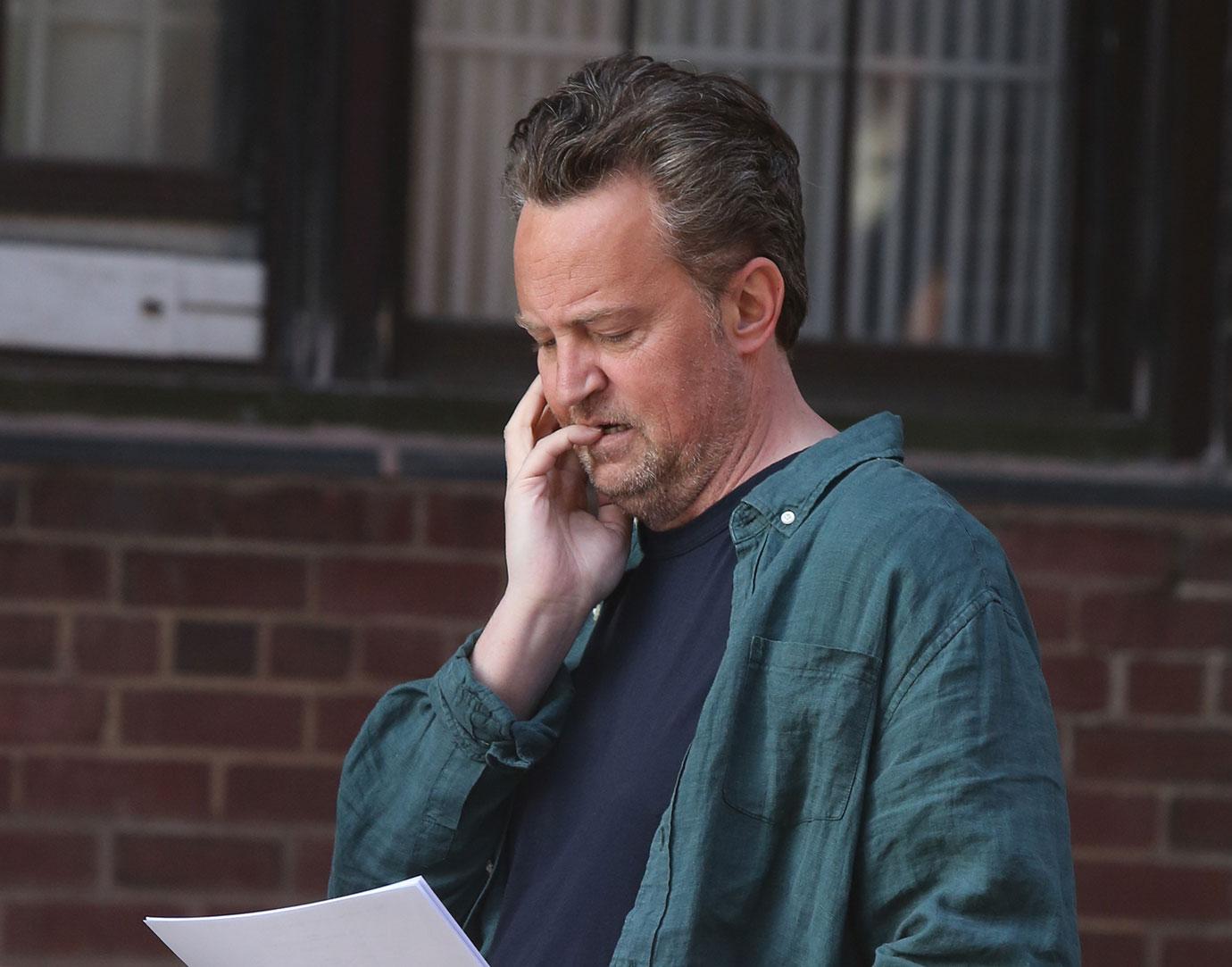 Matthew Perry in Forest Green Shirt Reading Papers on NYC Street