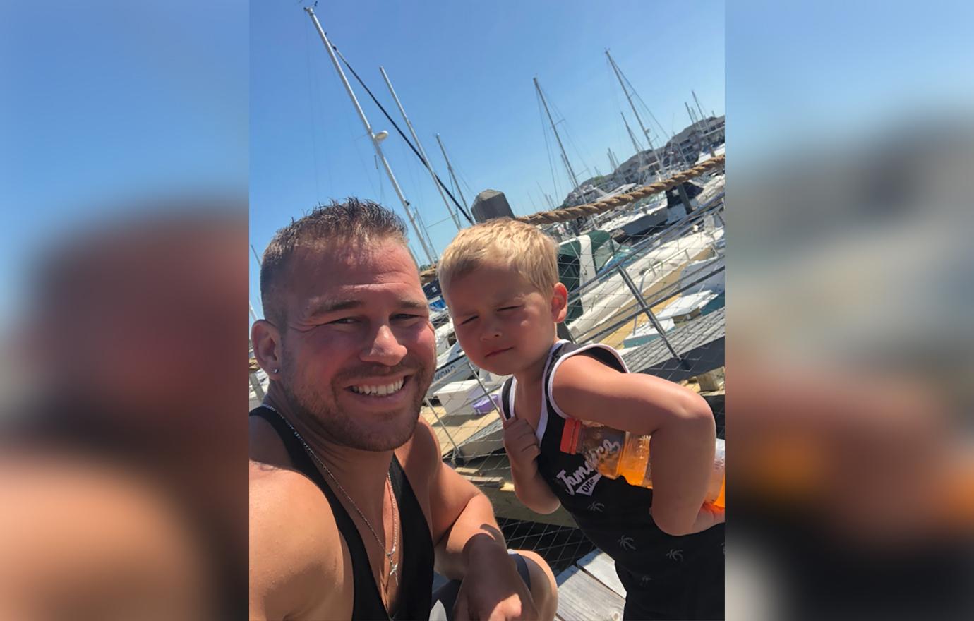 Nathan Griffith Sitting Smiling With Son Kaiser on Dock