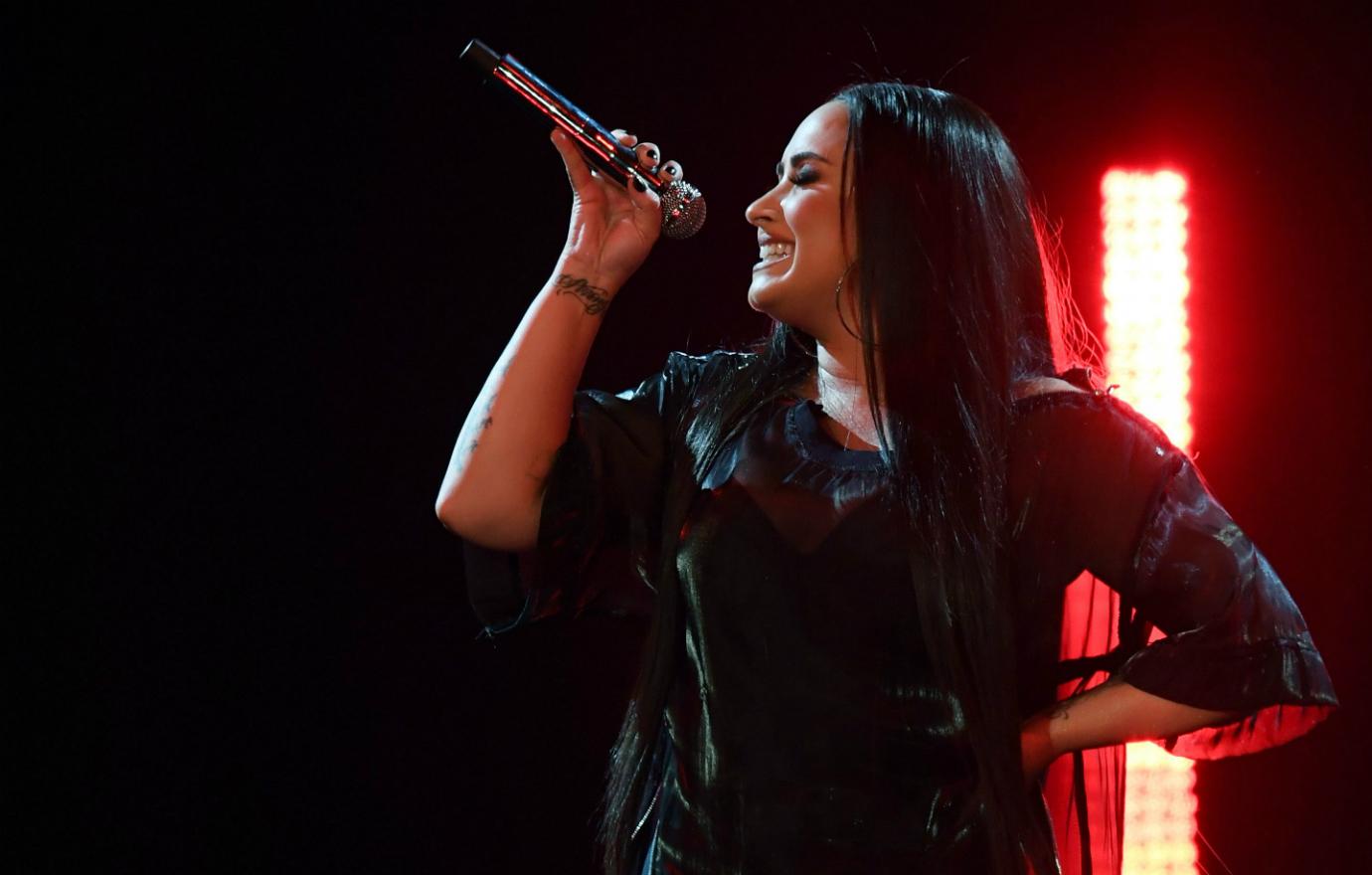 Demi Lovato performed in a black leather top as bright lights shined behind her.