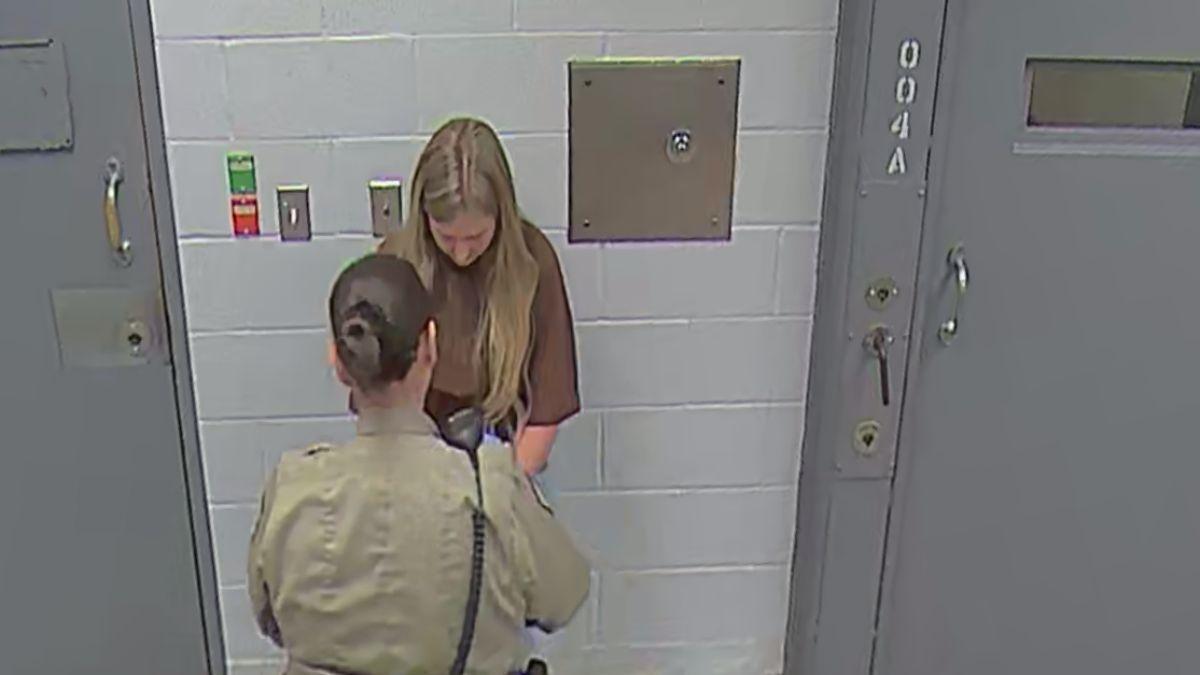 image of Authorities continued processing her before escorting her away with her hands secured behind her back.
