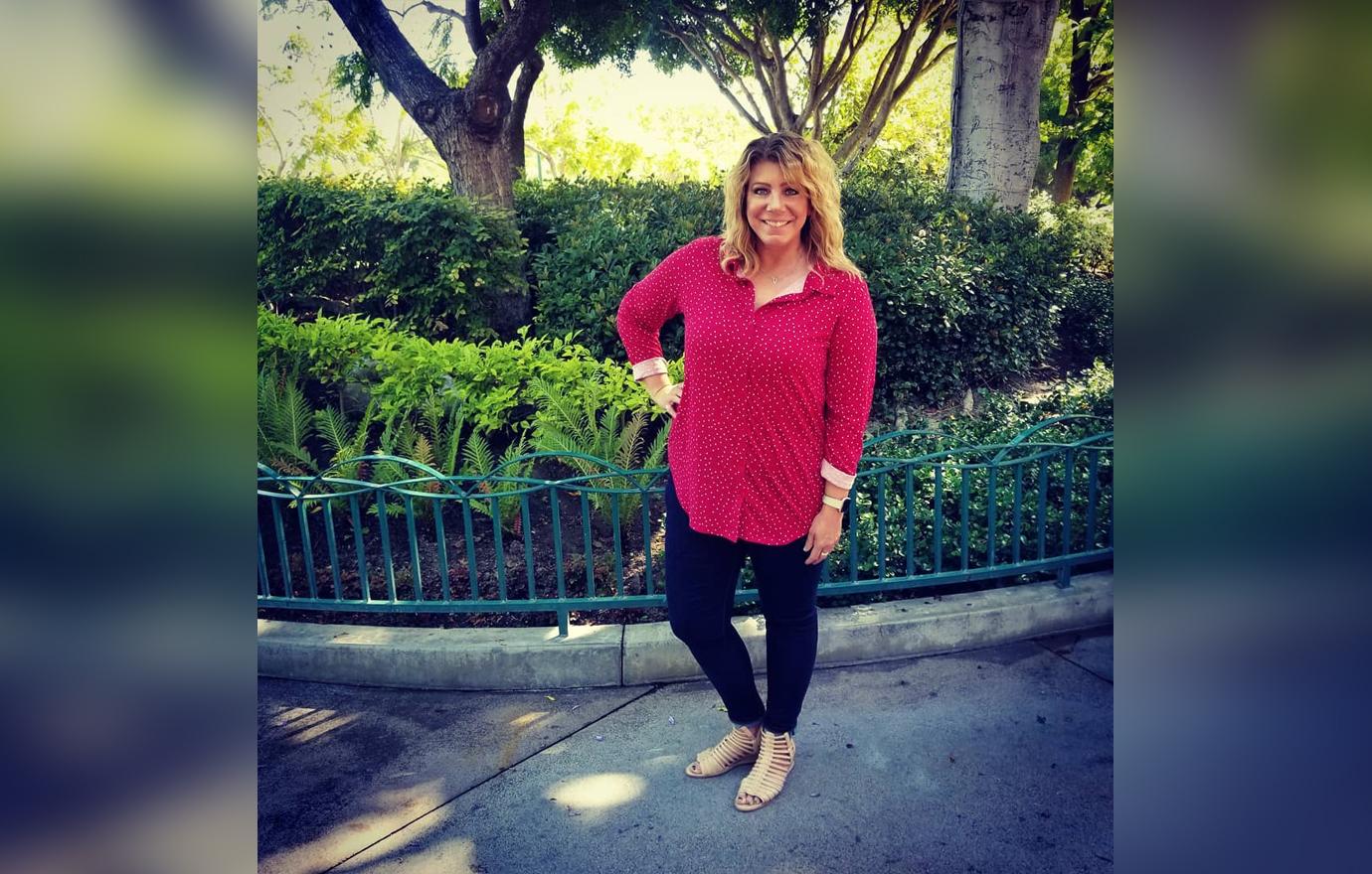 Meri Brown wears a magenta shirt with jeans as she pose for a photo.