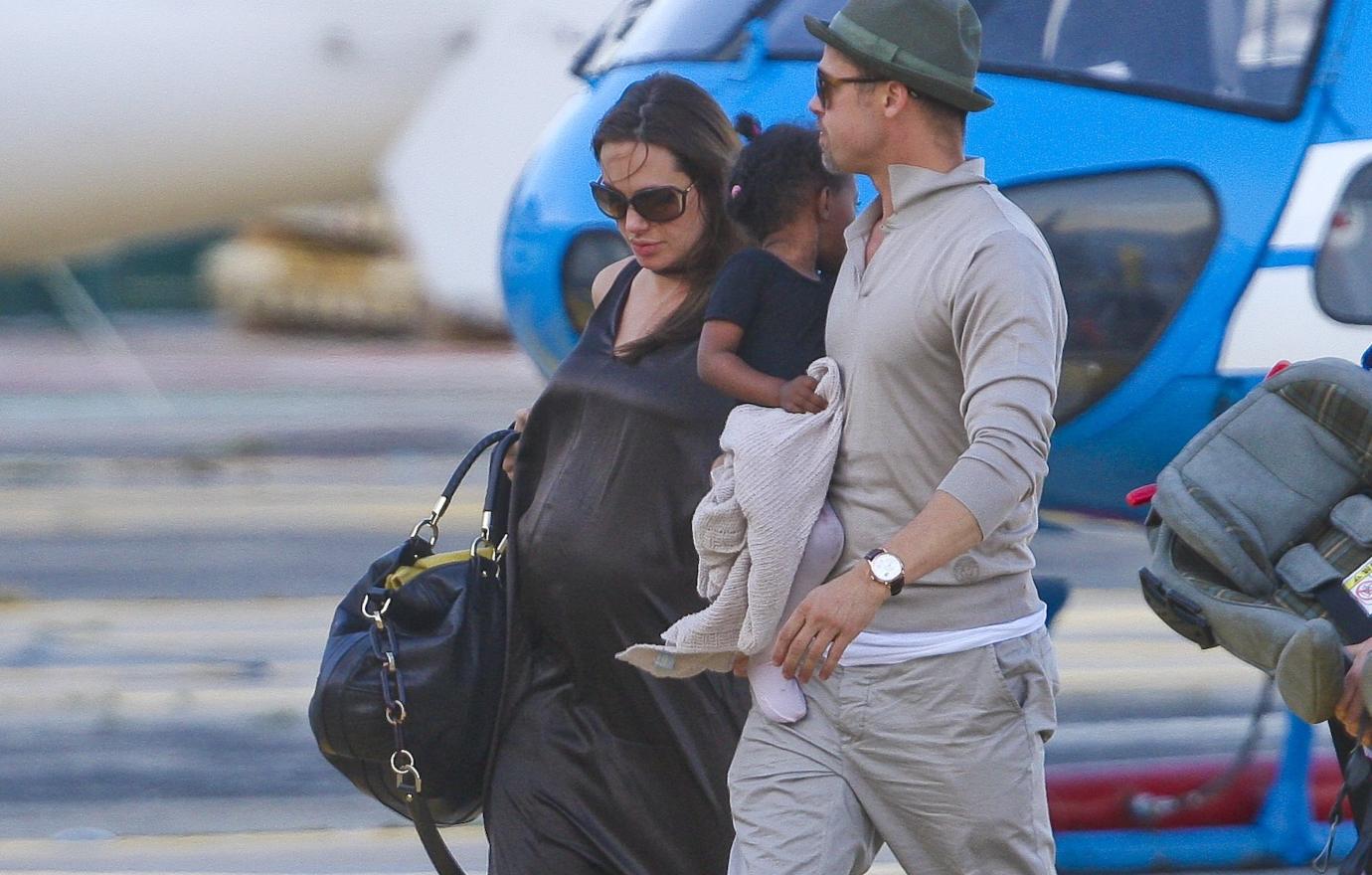 Brad and Angelina Jolie-Pitt walk with some of their kids near a plane