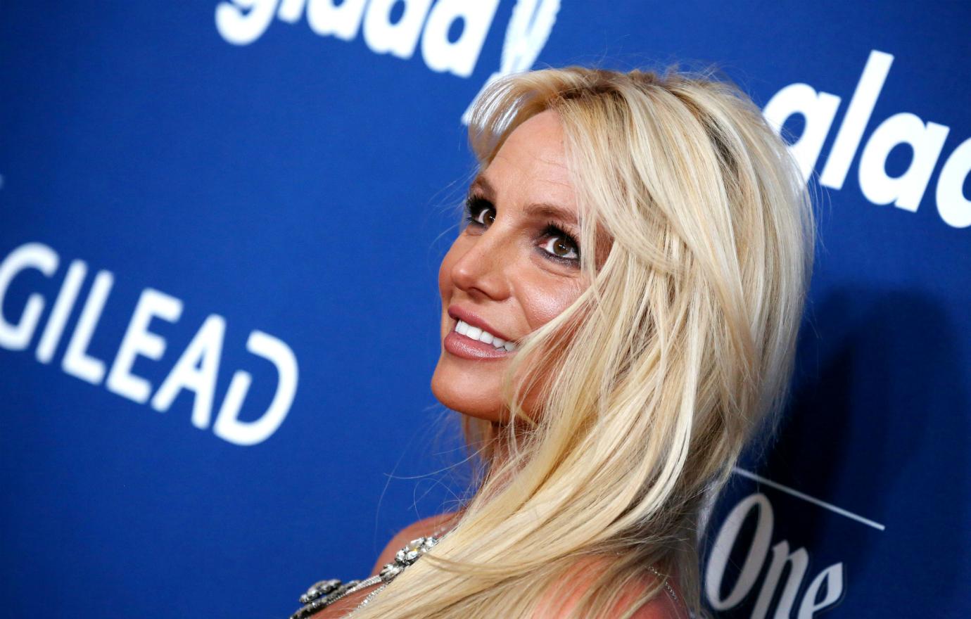 Britney Spears, in a strappy silver-fringed dress, smiles from the red carpet.