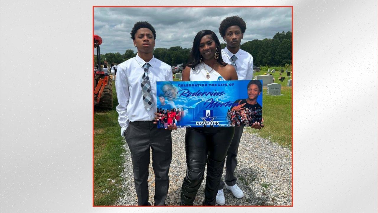 Photo of Tanisha Gunn holding a Rodderius Morton memorial banner with other relatives