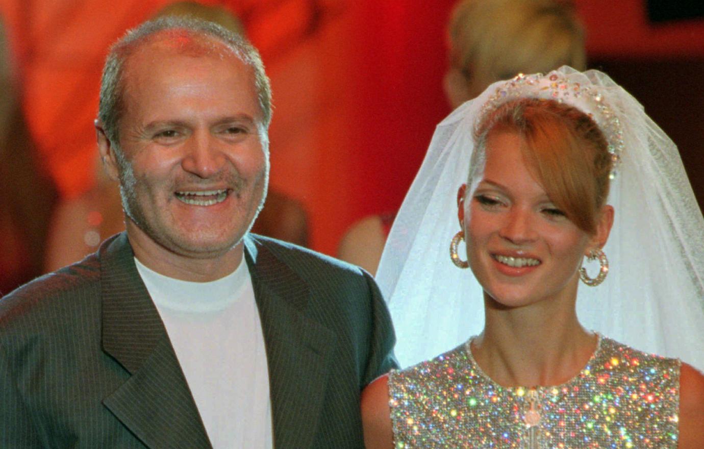 Gianni Versace, in a white top and black jacket, stands next to Kate Moss who wears a bridal veil.