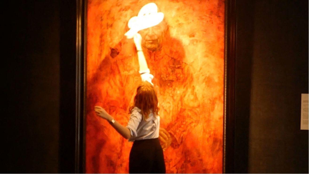 Picture of an Animal Rising activist vandalizing King Charles' portrait