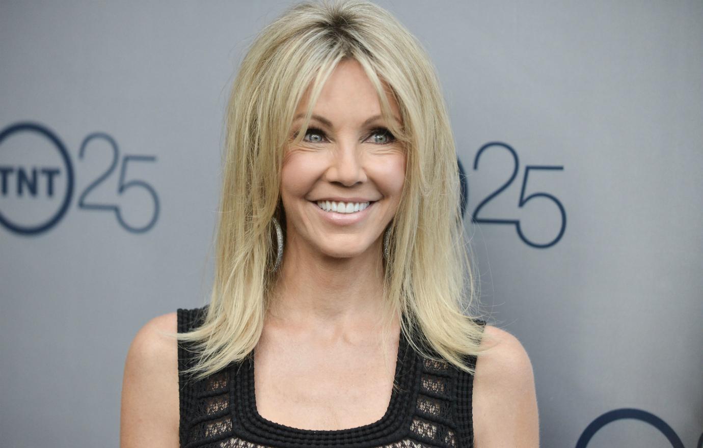 Heather Locklear in a black dress smiles on the red carpet.