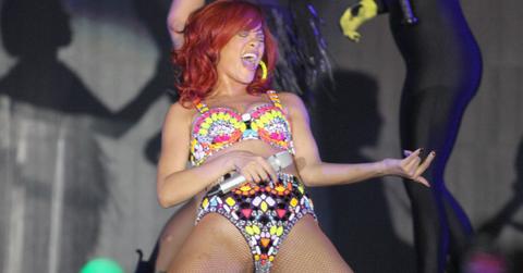 Rihanna sports a jeweled and colorful bikini on stage while doing the air guitar, rocking out to one of her songs in concert.