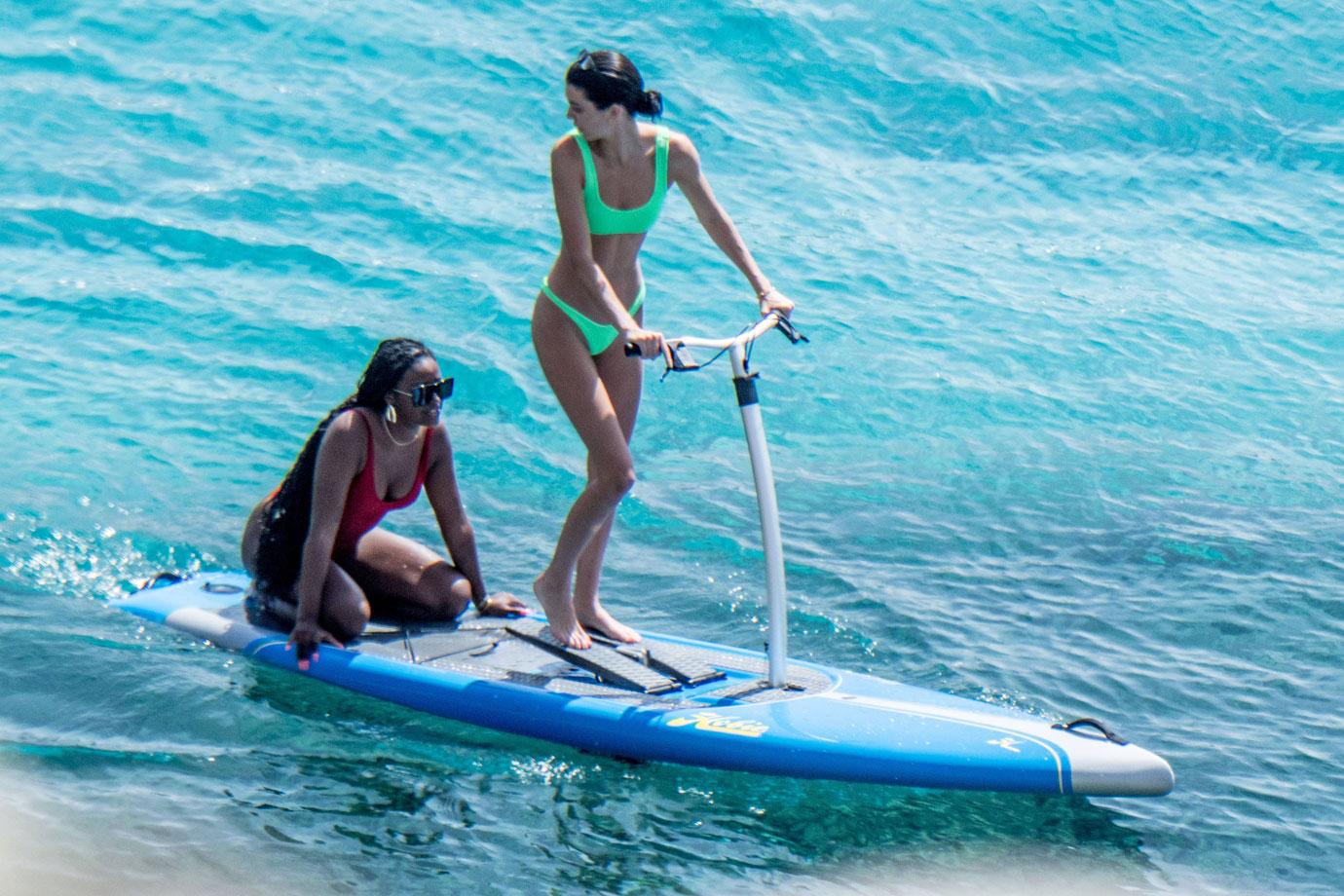 Kendall Jenner wears a neon-green bikini while having fun with friends paddle boarding in Mykonos.