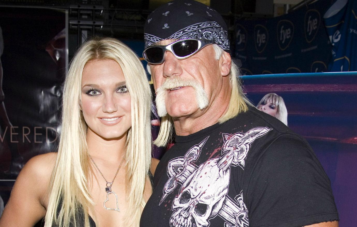 Brooke Hogan, in a black mini-dress, posed with her father … in a black T-Shirt and blue jeans, at an album release party for her.