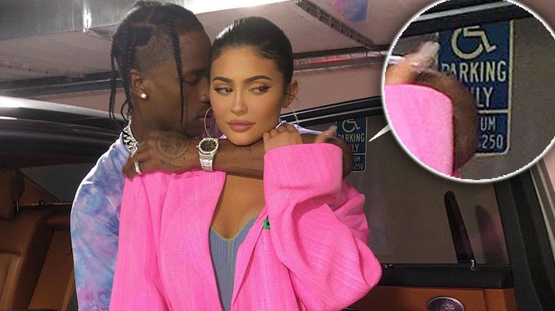 Travis Wearing Tie-Dye T-shirt Hugging Kylie Jenner Wearing Bright Pink Blazer and Blue Gray Top in fornt Of Their Car, Inset Handicap Parking Sign