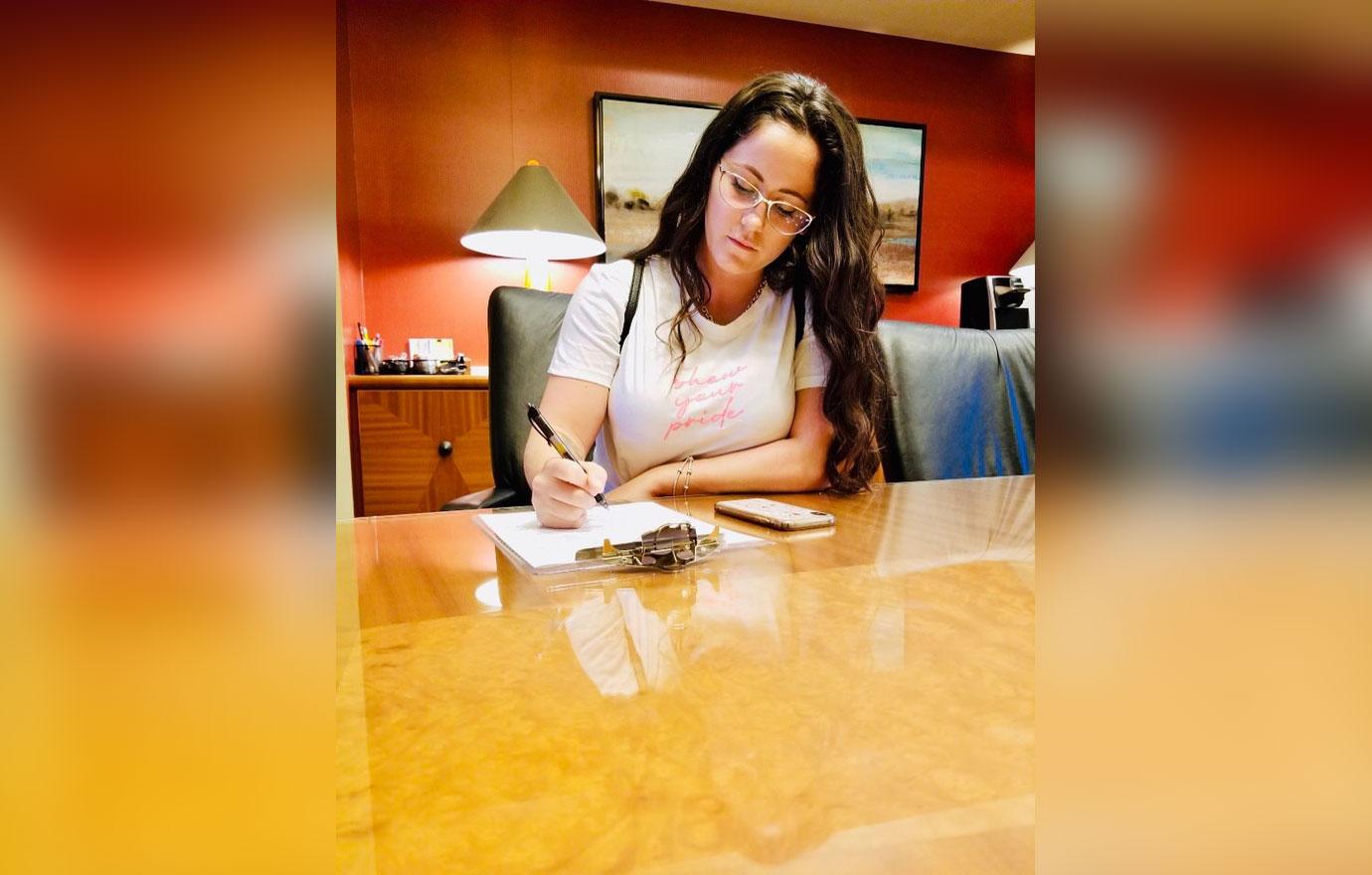 Jenelle Evans poses as she signs documents.