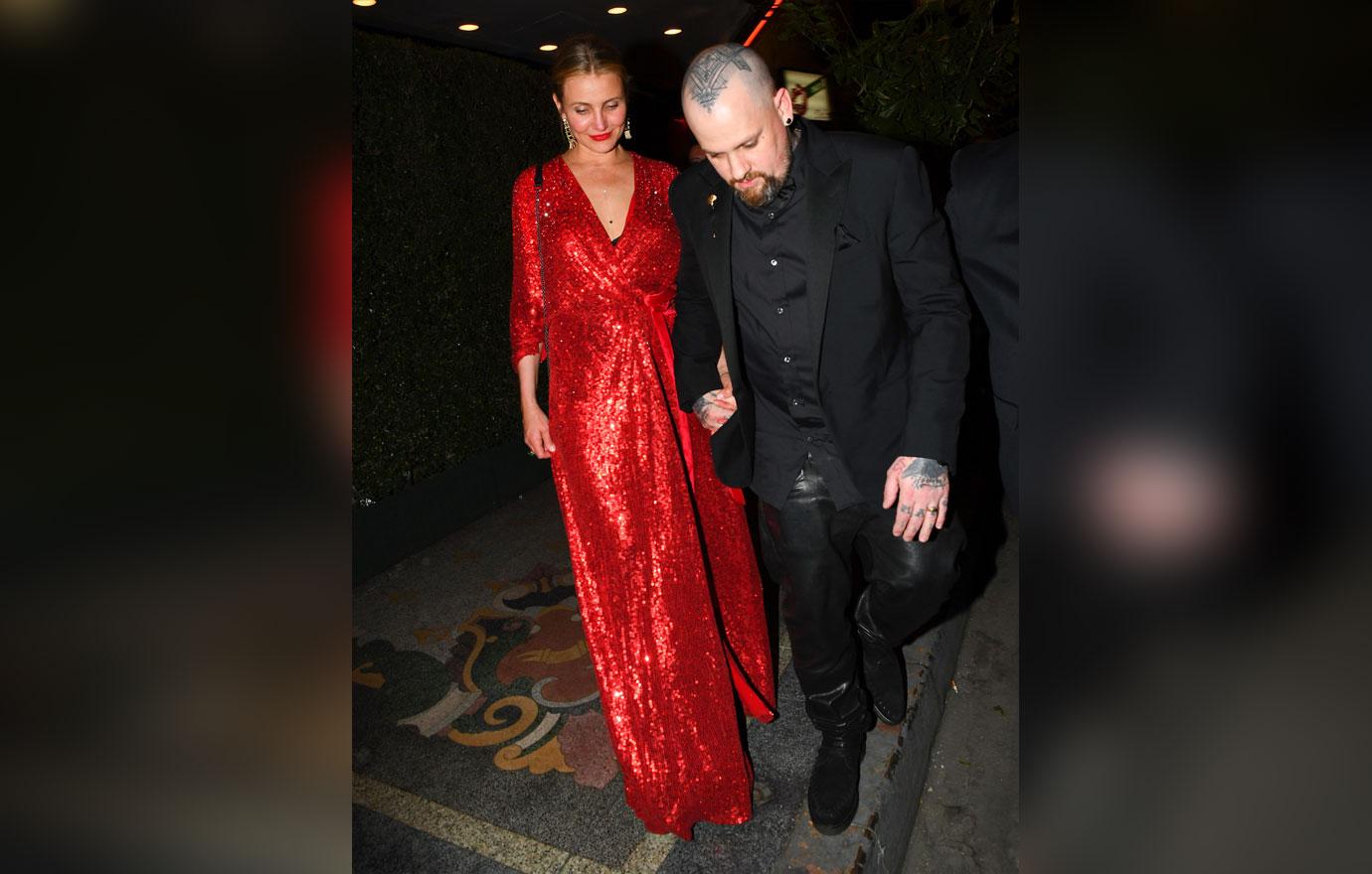 Cameron Diaz wears a red dress and Benji Madden wears a black suit.